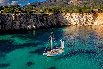 A sailboat is floating in the water near a cliff