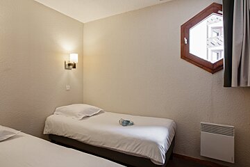 A small bedroom with two beds and a window