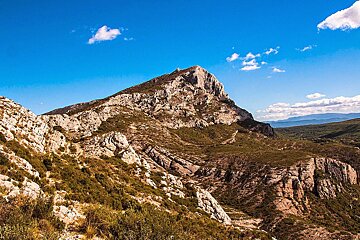 A mountain with a blue sky and clouds behind it