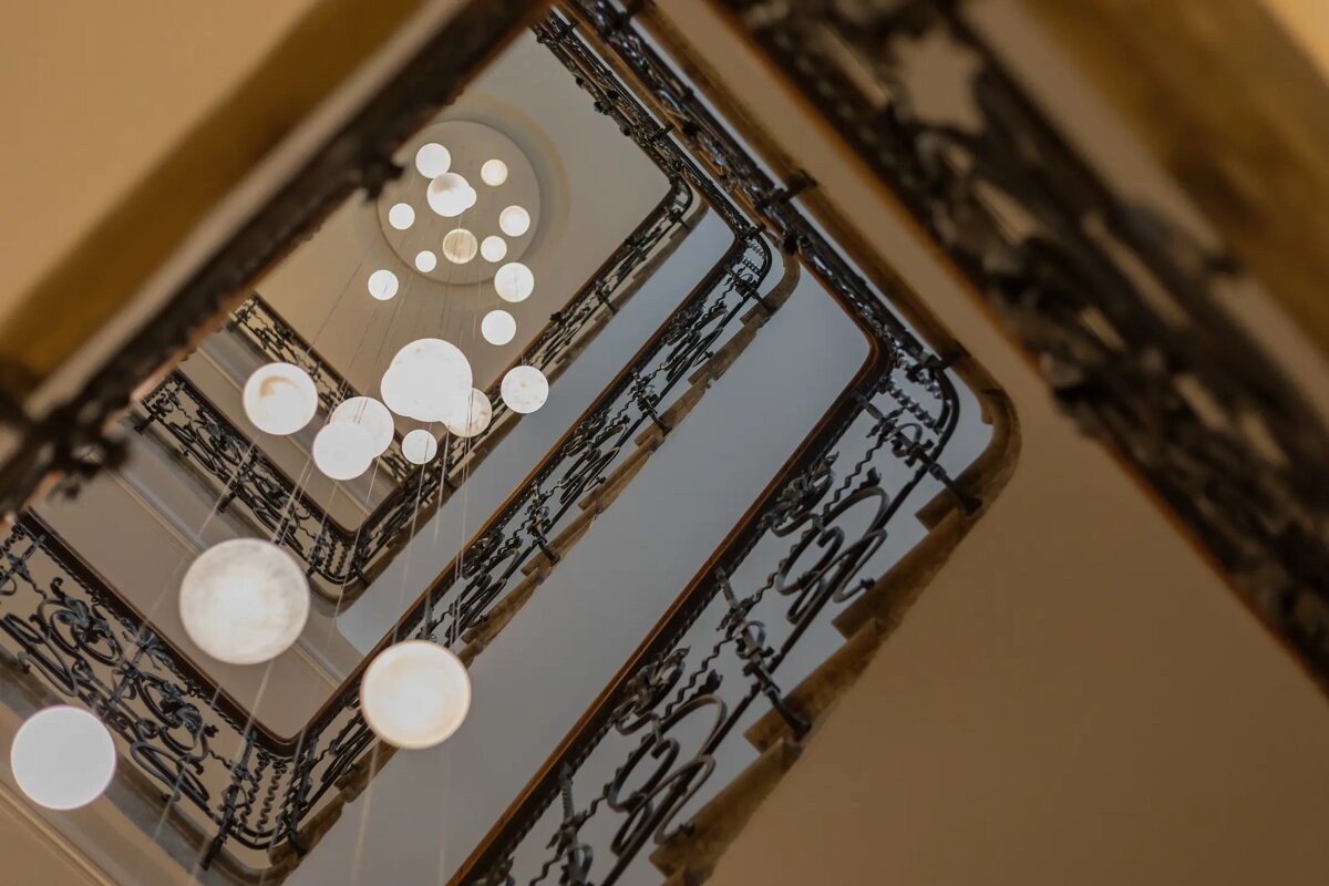 Looking up at a staircase with many lights hanging from the ceiling