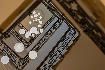Looking up at a staircase with many lights hanging from the ceiling