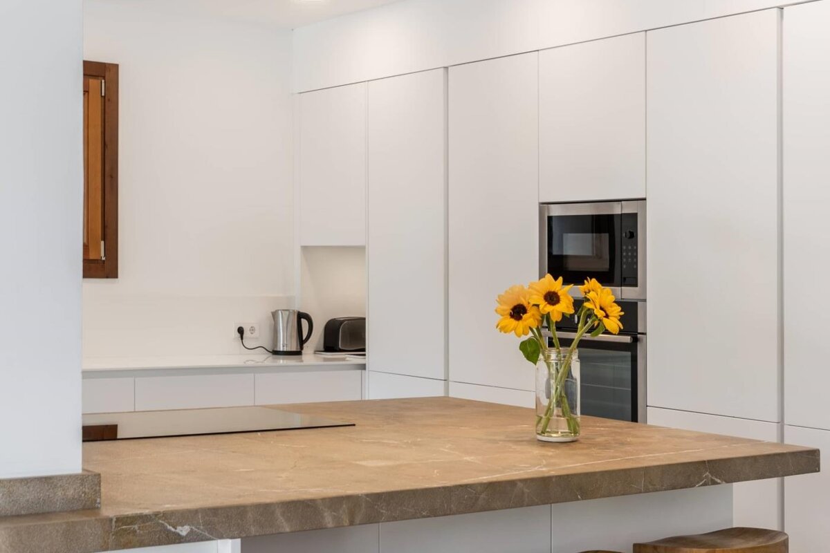 A kitchen counter with a vase of sunflowers on it