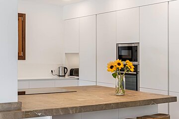 A kitchen counter with a vase of sunflowers on it