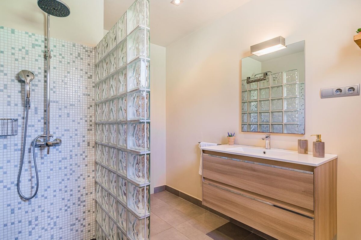 A bathroom with a walk in shower and a sink