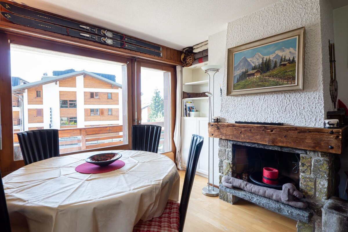 A dining room with a table and chairs and a painting on the wall
