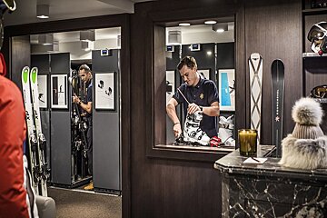 A man is working on a pair of skis that say continental