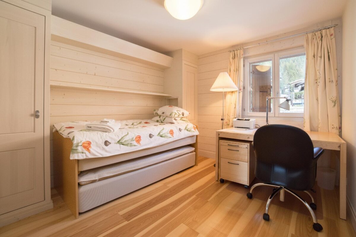 A bedroom with a single bed and a desk with a printer