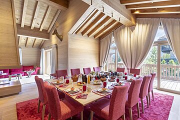 A dining room with a long table and pink chairs