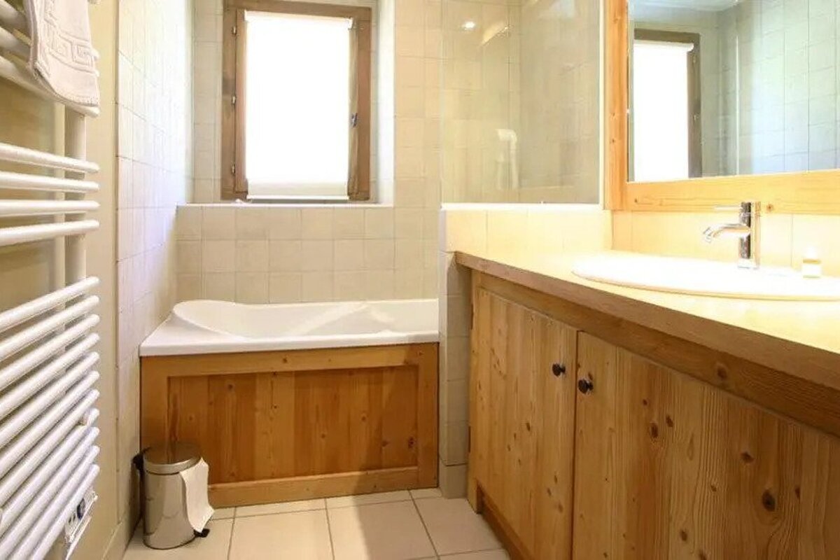 A bathroom with wooden cabinets a sink and a bathtub