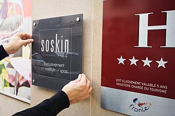 A person is putting a sign on a wall that says soskin