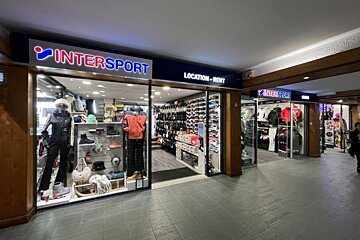 An Intersport store featuring winter apparel, footwear, and ski accessories for sale and rent, displayed in a brightly lit indoor commercial space.