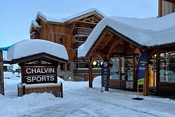 A snow-covered ski village features rustic wooden buildings and a prominent