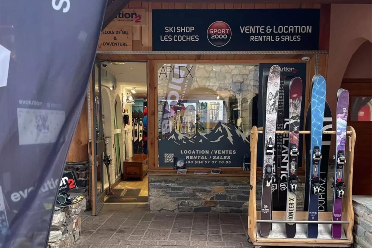 A ski shop facade with skis displayed outside for rental and sales. Signs indicate