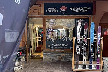 A ski shop facade with skis displayed outside for rental and sales. Signs indicate