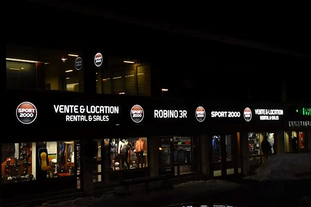 A brightly lit Sport 2000 store at night, advertising 