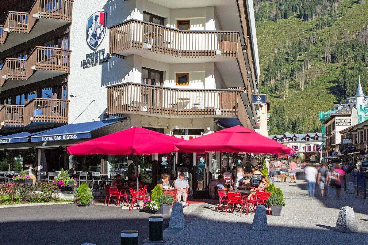 A hotel bar bistro with red umbrellas in front of it