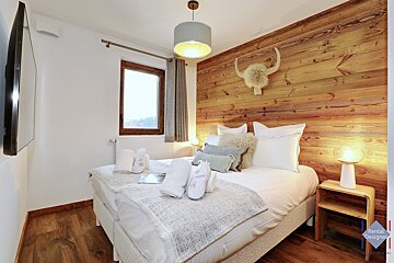A bedroom with a wooden wall and a bed