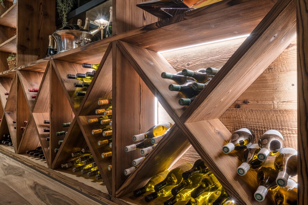 A row of wooden shelves filled with bottles of wine