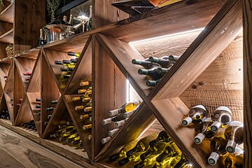 A row of wooden shelves filled with bottles of wine