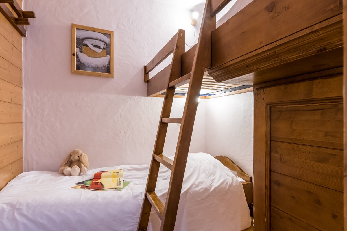 A bunk bed with a ladder and a picture on the wall above it