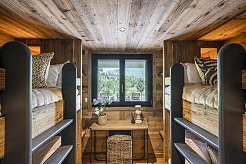 A room with bunk beds and a window with a view of the mountains