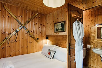 A bedroom with skis on the wall and a picture on the wall above the bed