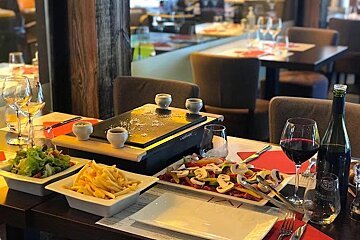 A restaurant table with plates of food and a bottle of wine