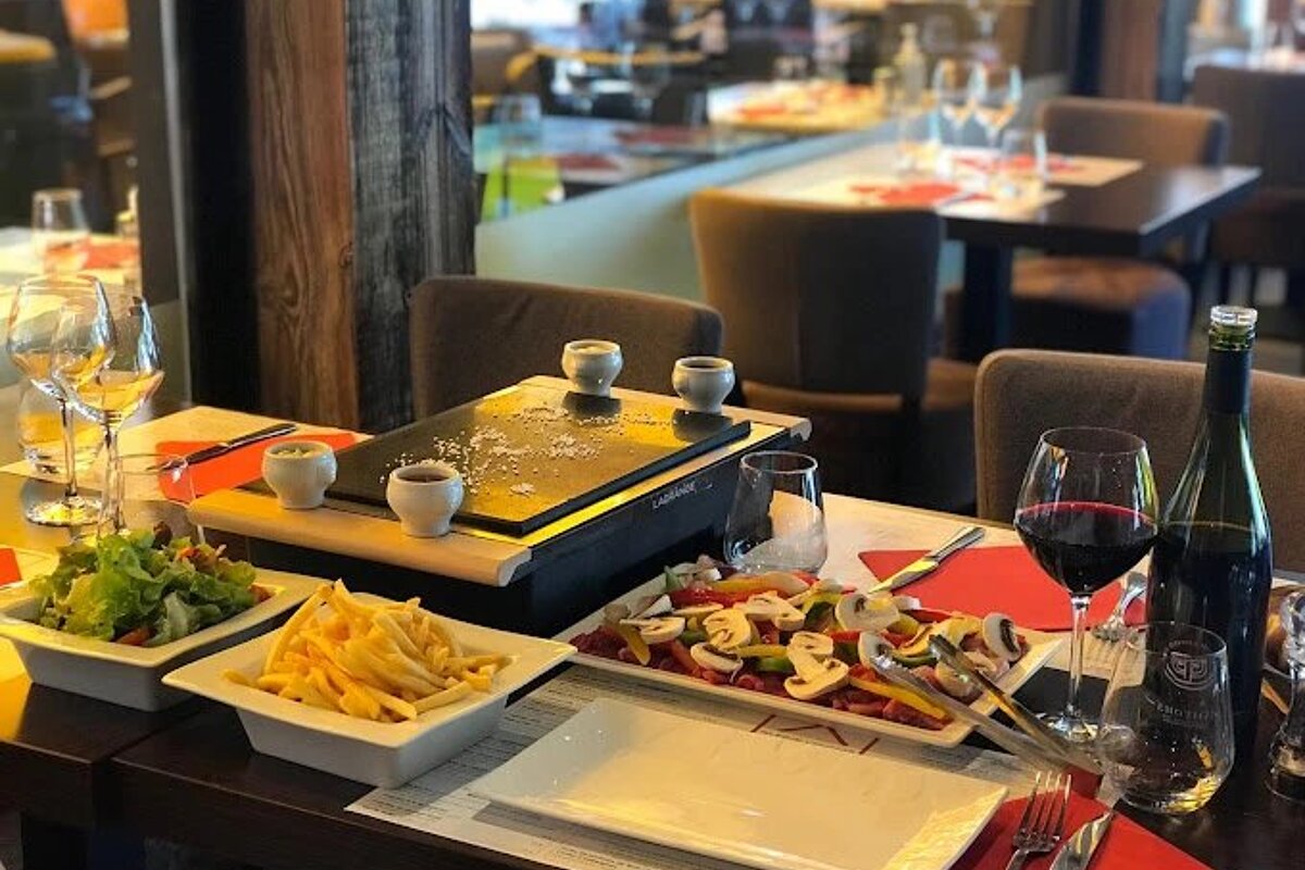 A restaurant table with plates of food and a bottle of wine