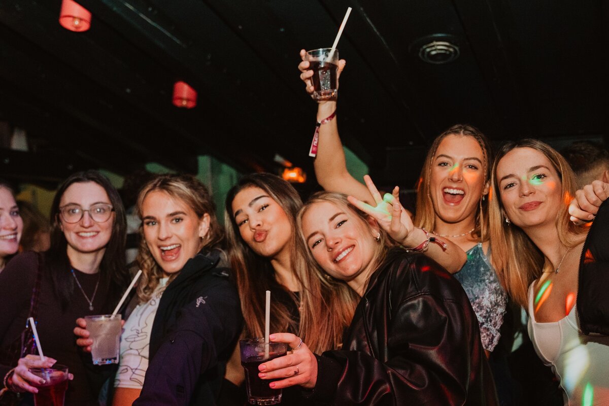 A group of young women are posing for a picture while holding drinks