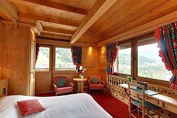 A bedroom with a bed and chairs and a desk