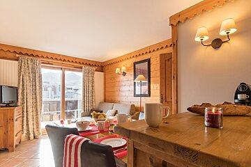 A candle sits on a wooden table in a living room