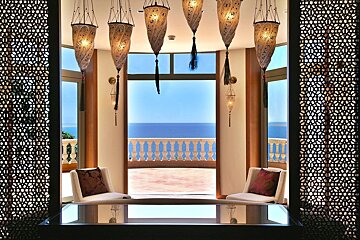 A room with a table and chairs with a view of the ocean