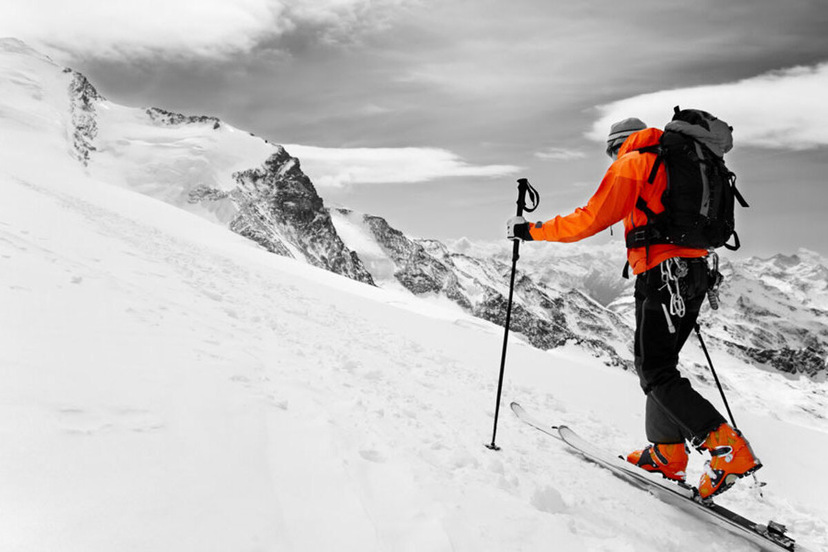 ski tourer in orange jacket & boots going up hill