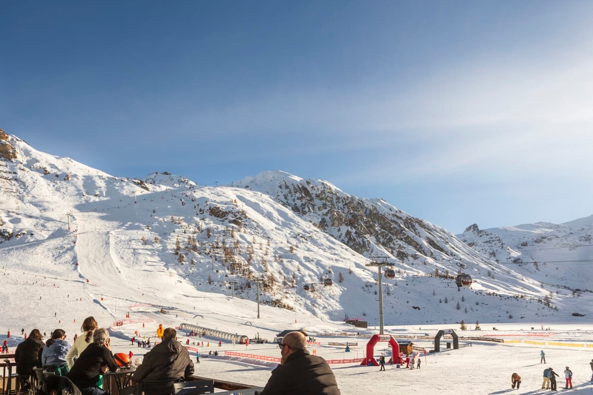 A group of people are watching skiers on a ski slope