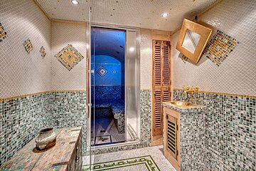 A bathroom with green and white tiles and a sink