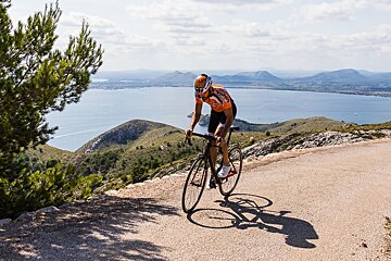 A person riding a bike on a road with a lake in the background