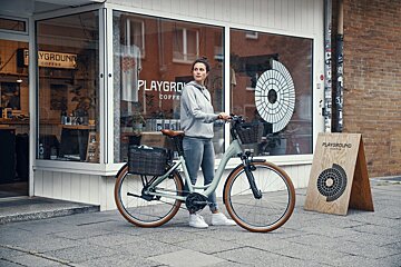 A woman riding a bike in front of a playground coffee shop