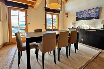 A dining room with a table and chairs and a picture on the wall