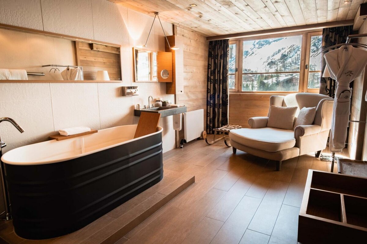 A bathtub in a bathroom with a chair and a window