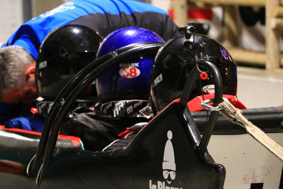 people in helmets in a bob sled