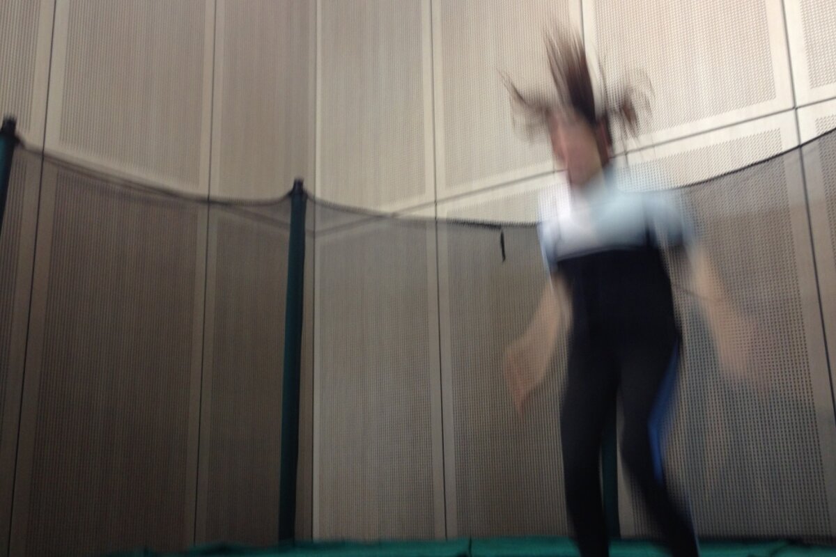 a woman mid jump on a trampoline with her hair in the air