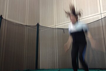 a woman mid jump on a trampoline with her hair in the air