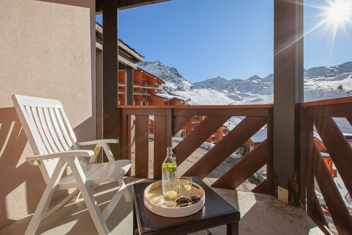 A balcony with a chair and a tray of drinks