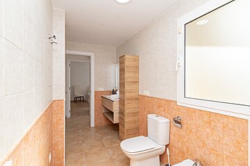 A bathroom with a toilet a sink and a window
