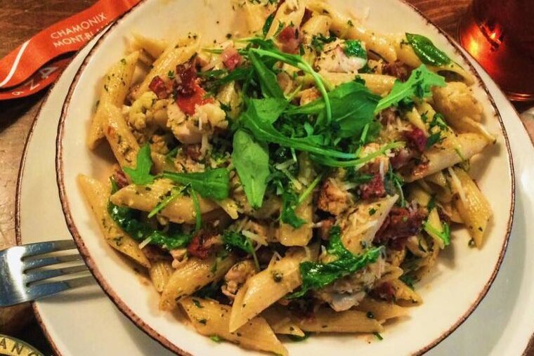 A plate of pasta sits on a table next to chamonix mont blanc