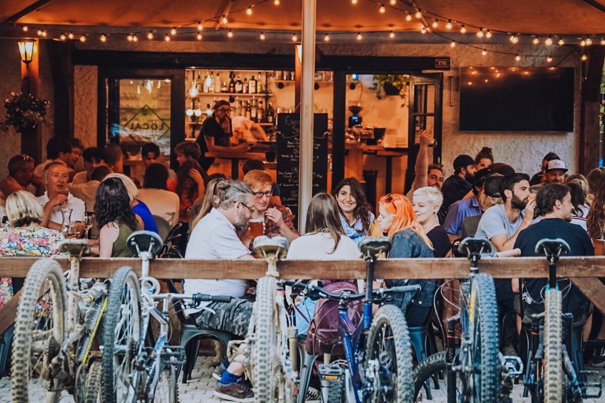 A group of people sitting outside a restaurant with bikes parked in front of them