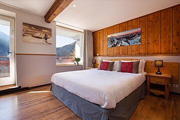 A bedroom with a large bed and a painting on the wall