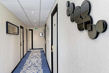 A hallway with a blue rug and mirrors on the wall