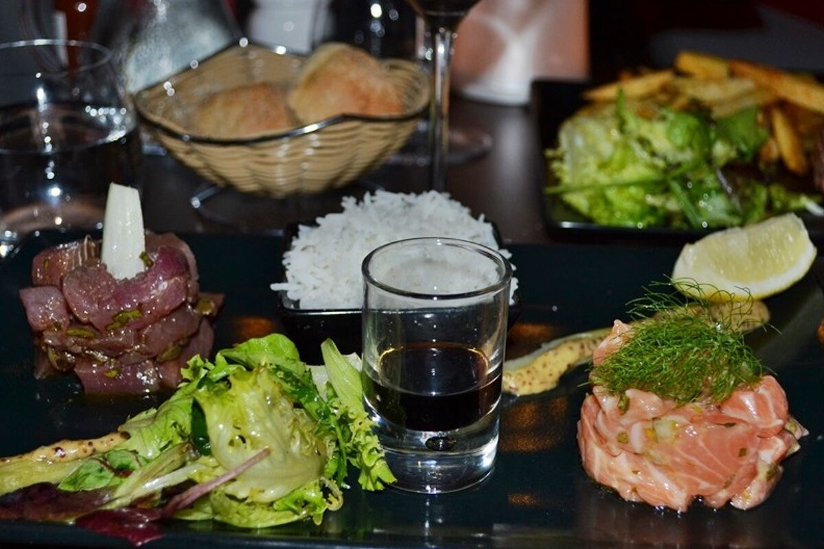image of tuna and salmon tartare with rice and salad and a glass of soy sauce