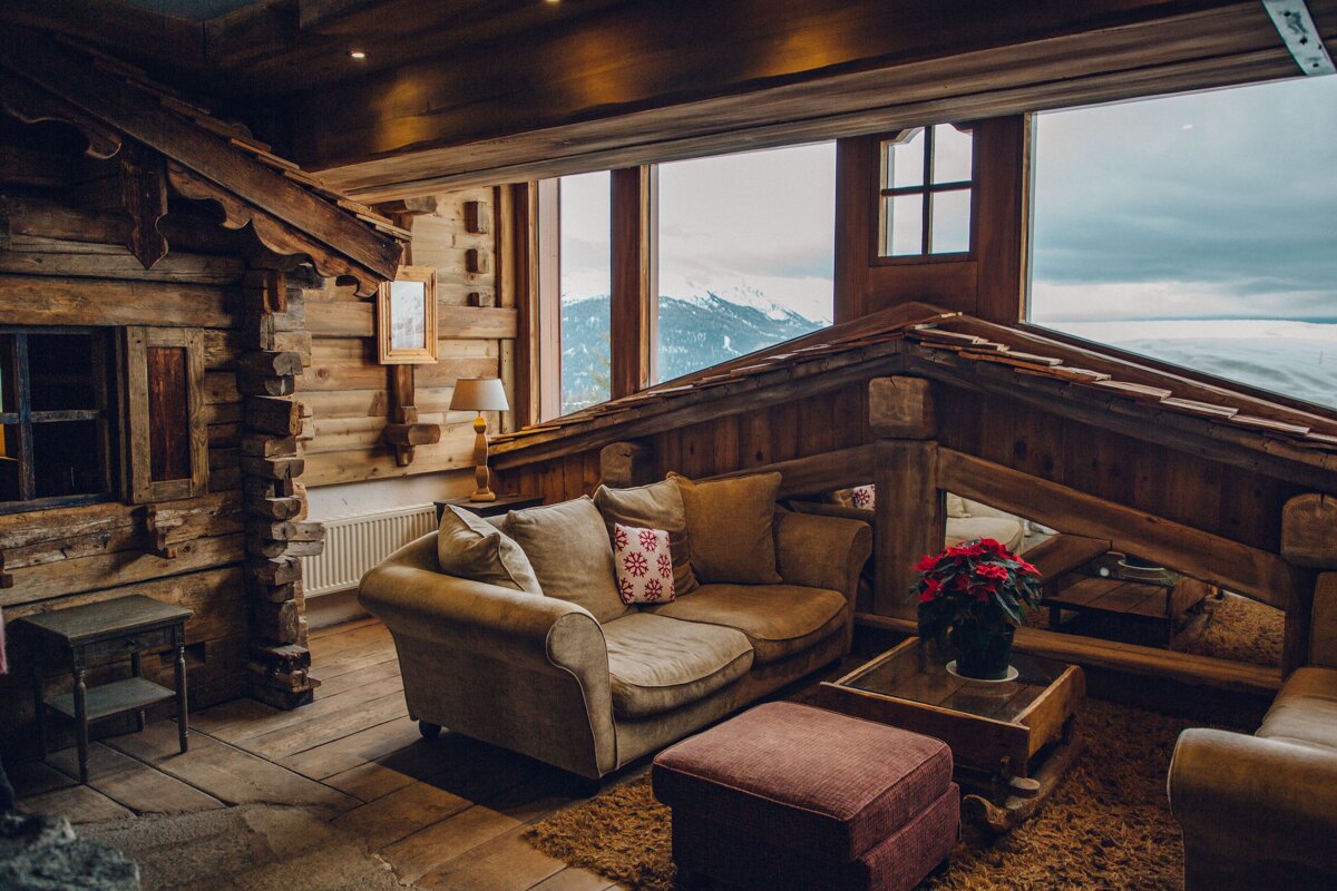 A living room in a log cabin with a couch and ottoman